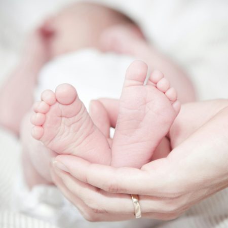 Tender photo of a mother's hands holding her newborn's feet, symbolizing love and care.